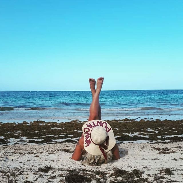 девушка на пляже на фоне водорослей