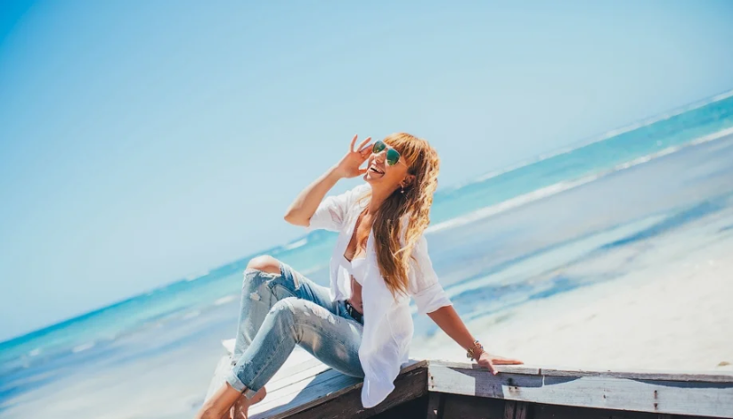 Рубашка и голубые джинсы — образ городской, но яркие солнечные очки и купальник создают пляжное настроение
