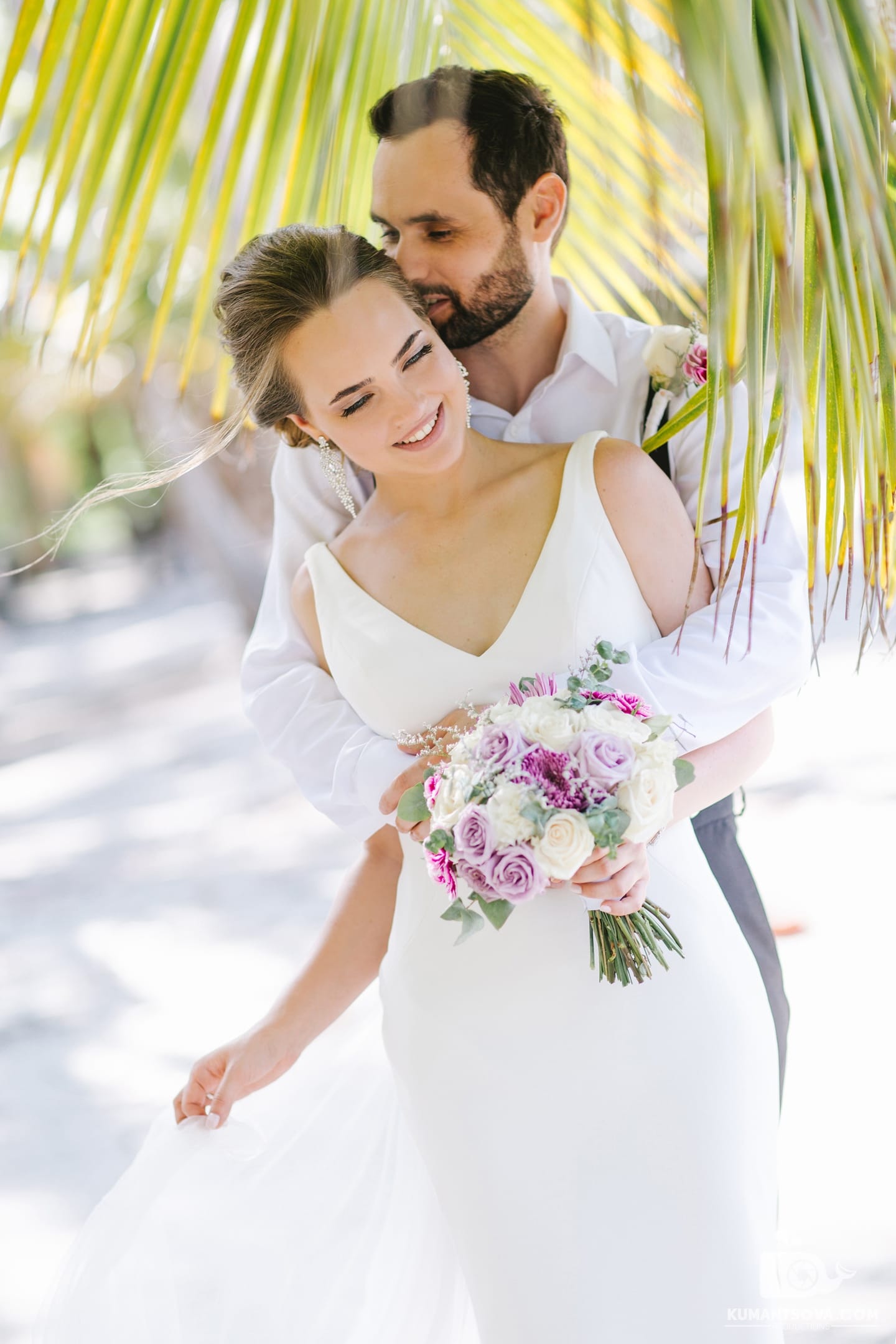 супруги обнимаються под пальмой